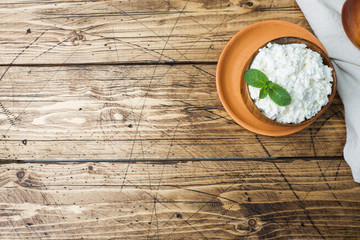 Obraz na płótnie Canvas Homemade cottage cheese with mint in a bowl on old wooden table. Copy space