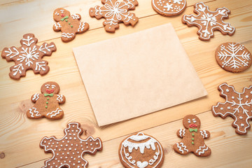 Closeup of decorated Christmas gingerbread cookies with blank paper on rustic background