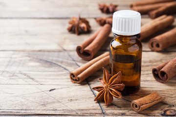 Fototapeta premium Essential aroma oil with cinnamon and star anise on wooden background. Selective focus.