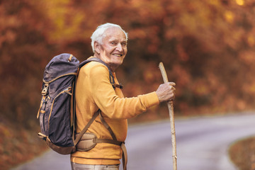 Senior man hiking in autumn forest.