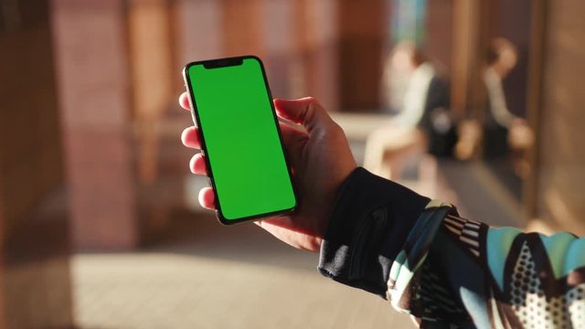 Close up man hand using phone with vertical green screen background sunlight street people city blurred internet chrome outdoor cellular smartphone scrolling tapping communication slow motion