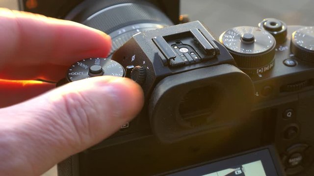 Close shot of photographer turning the ISO dial on a mirrorless camera