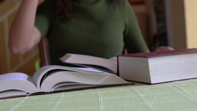 Woman flipping pages of a book and then put down her reading glasses on top of a book. Tired from study concept.