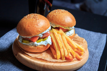 Two fish burgers with pieces of fish and fries. Burgers on a dark background.