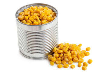 Canned sweet corn in an open metal tin next to spilled sweet corn isolated on white.