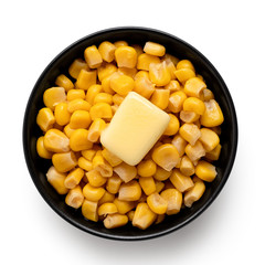 Canned sweet corn with a knob of butter in a black ceramic bowl isolated on white. Top view.