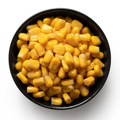 Canned sweet corn in a black ceramic bowl isolated on white. Top view.