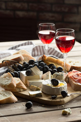 different varieties of cheese with fruits, nuts, dried fruits and kitchen utensils for cheese plate, nuts, dried fruits, wine and kitchen utensils for cheese plate