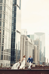 Beautiful bride in a long white dress. Handsome fiance in a blue suit. Couple in a big city