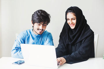 Middle eastern muslim woman and man working together on a laptop in office