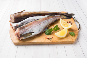 Raw fresh Pollock fish on a wooden Board with lemon