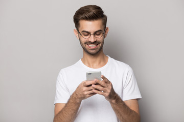 Smiling caucasian man in glasses using modern smartphone