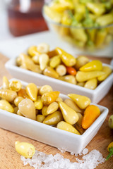 Marinated chili peppers with fresh green peppers on wooden background.