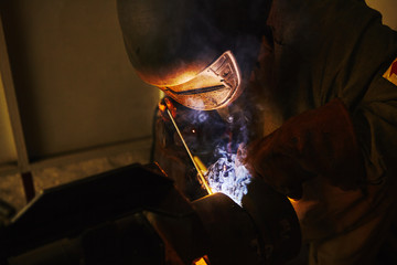 Male in face mask welds with welding