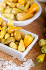 Marinated chili peppers with fresh green peppers on wooden background.