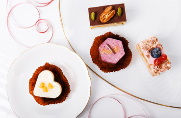 Concept for cafe or bakery with desserts, festive banner.Small cakes with different stuffing in the shape of a heart