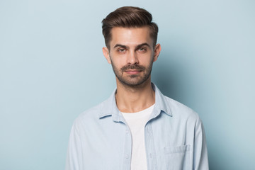 Fototapeta premium Headshot of serious caucasian young man posing on blue background