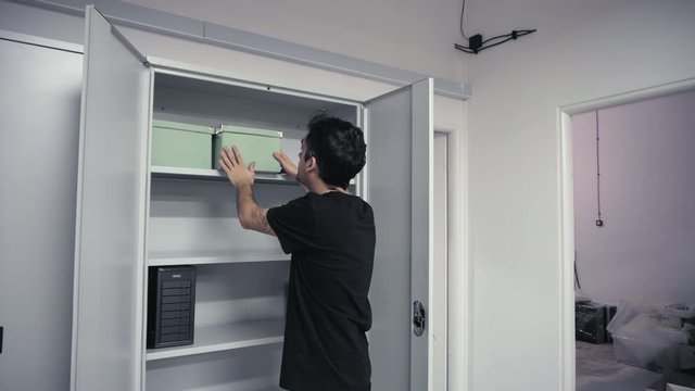 Man inserting cardboard box into cabinet