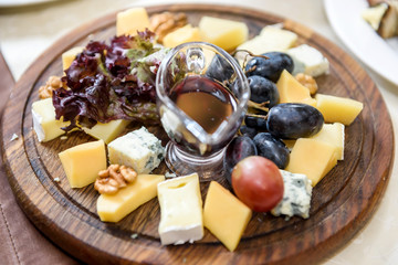 Cheese plate with olive oil and grape in restaurant close up. Food concept