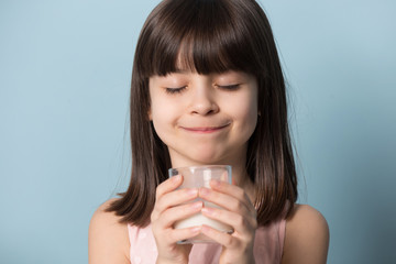 Happy little girl drink plant delicious milk from glass