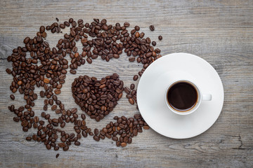 Espresso coffee on a wooden table with coffee beans in the shape of a heart