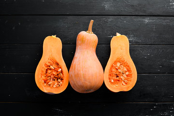 Fresh pumpkin, autumn vegetables. On a black stone background. Top view. Free copy space.