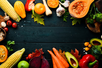Fresh seasonal vegetables on a black stone background: Pumpkin, tomato, avocado, cucumber, onion, carrot. Autumn food. Top view. Free copy space.