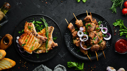 Barbecue. Steak and kebab on a black plate. Top view. Free copy space.