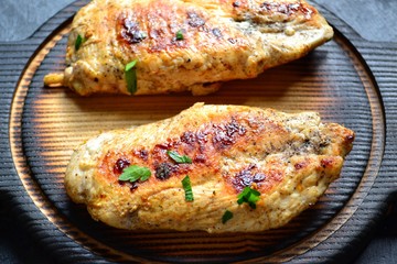 Grilled chicken breast. Chicken fillet with broccoli and mushrooms. Appetizing chicken meat on a wooden board on a dark background