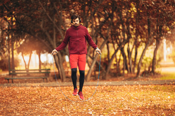 Man jumping rope outdoors on sunny autumn morning.