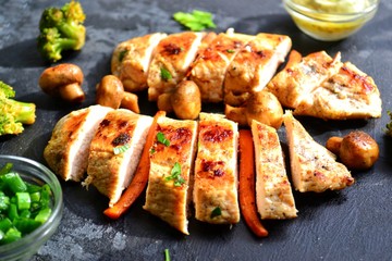 Grilled chicken breast. Appetizing grilled chicken fillet. Meat with vegetables, broccoli and mushrooms. Food on a dark background