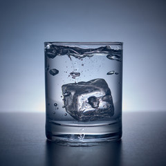 glass with water and ice against a dark background