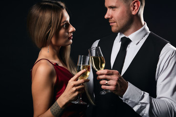 young elegant woman in red dress and handsome man in white shirt, tie enjoying spending time in the party, isolated black background, relationship. love