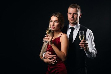 serious couple holding glasses looking aside, close up portrait, isolated black background, studio shot. copy space