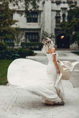 Fototapeta na wymiar Beautiful bride in a long white dress. Woman with bouquet of flowers. Lady dancing in a park