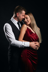 young pleasant man in shirt taking off his woman's dress, close up portrait, isolated black background, studio shot , copy space