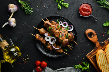 Juicy skewers of meat in a black plate. Barbecue, kebab. Top view. Free copy space.