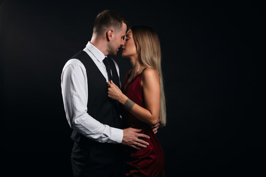 first kiss, woman and man enjoying kissing in the dark room, cose up portrait, isolated black background, studio shot