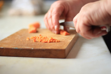 women's hands cut carrot for dinner