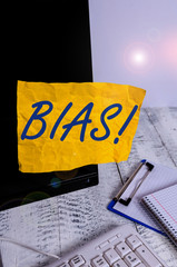 Conceptual hand writing showing Bias. Concept meaning inclination or prejudice for or against one demonstrating group Note paper taped to black screen near keyboard stationary