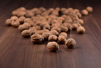 Walnuts on a wooden background stock images. Pile of walnuts with nutshell. Walnuts close up on wooden background. Walnuts on the table