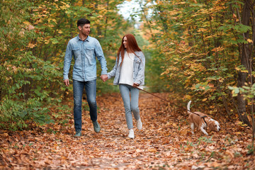 Fototapeta premium Young romantic couple walking with beagel in autumn park, smiling.full length, lifestyle, free time