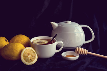 Teapot and cup of tea with lemon slice on a black background, isolated