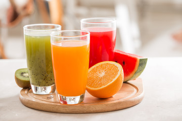 Fresh juices smoothie three glass red green orange tropical fruits water melon, kiwi, orange. Selective focus