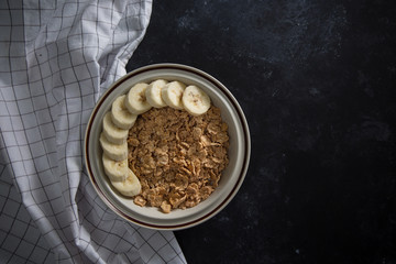 Organic healthy oatmeal porridge with fresh bananas. The white porcelain bowl with napkin