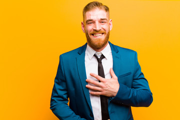 young red head businessman laughing out loud at some hilarious joke, feeling happy and cheerful,...