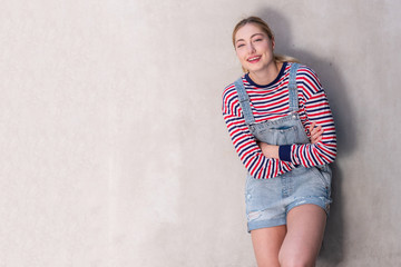  teenage girl with blond hair laughing with arms crossed by white wall