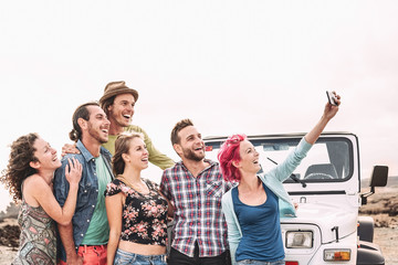 Happy friends taking selfie with mobile smartphone next offroad convertible car - Millennial young...