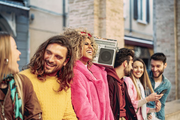 Group of friends having fun listening music with vintage boombox - Happy young people making party outdoor - Youth culture and millennial lifestyle concept