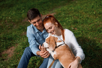 smiling romantic couple teaching dog to give its paw, close up cropped photo, tender warm feeling emotion